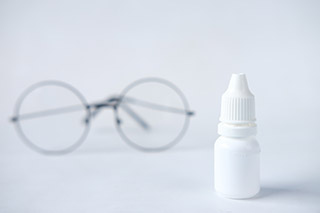 Eye drop medicine in front of reading glasses.